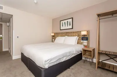 a bedroom with a large bed with white sheets at The Aviator, formerly Smugglers Cove, Clacton On Sea by Marston's Inns in Clacton-on-Sea