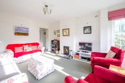 a living room with red furniture and a tv at Lake Cottage - A large holiday home in Thorpeness - Close to the beach and The Meare - Aldeburgh Coastal Cottages in Thorpeness