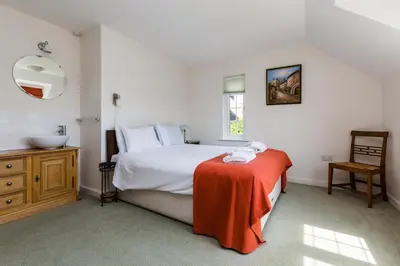 a bedroom with a bed with a red blanket and a sink at Lake Cottage - A large holiday home in Thorpeness - Close to the beach and The Meare - Aldeburgh Coastal Cottages in Thorpeness
