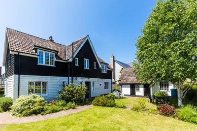 a black and white house with a yard at Lake Cottage - A large holiday home in Thorpeness - Close to the beach and The Meare - Aldeburgh Coastal Cottages in Thorpeness
