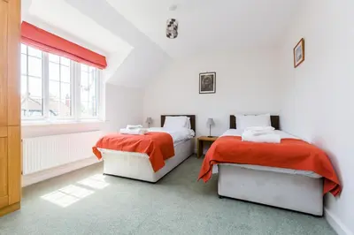 two beds in a white room with a window at Lake Cottage - A large holiday home in Thorpeness - Close to the beach and The Meare - Aldeburgh Coastal Cottages in Thorpeness