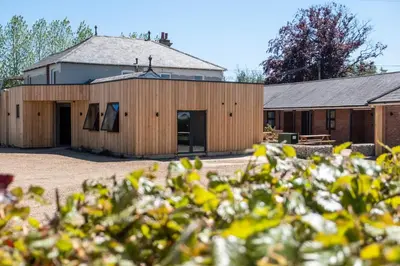 a barn with a building in the background at Oak - Three Tuns Apartments, Pettistree, Wickham Market - by Aldeburgh Coastal Cottages in Pettistree