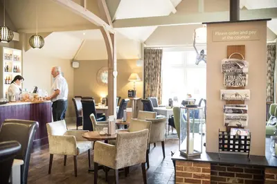a man standing at the counter of a restaurant at Breckland Lodge in Attleborough