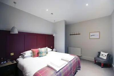 a bedroom with a large bed and a chair at The Coach House in Potton