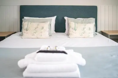 a white bed with two towels and pillows on it at The Oyster Smack in Burnham on Crouch