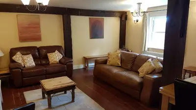 a living room with two leather couches and a table at The Pelican Guesthouse in Ashwellthorpe