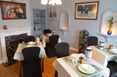 a dining room with tables and chairs and a fireplace at Elmcroft Guest House in Epping