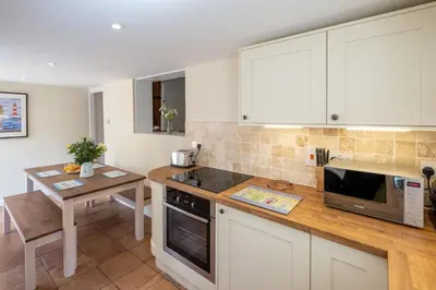 a kitchen with white cabinets and a wooden counter top at Little Tern Cottage in Aldeburgh