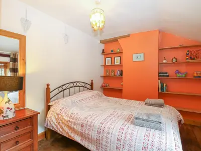 a bedroom with a bed with an orange wall at 3 Station Cottages in Wymondham