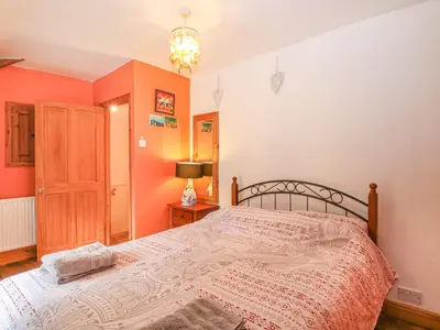 a bedroom with a large bed with orange walls at 3 Station Cottages in Wymondham