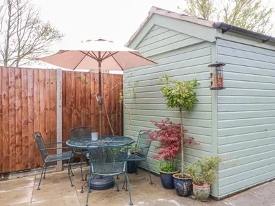 a patio with a table and an umbrella at 3 Station Cottages in Wymondham