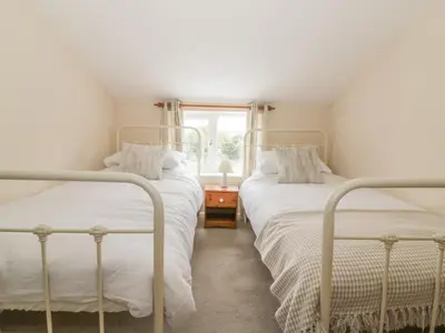 two beds in a white room with a window at 2 Hillside Cottages in Ipswich