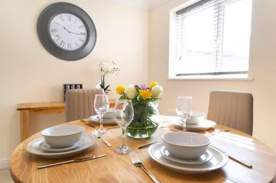 a wooden table with a vase of flowers and a clock at Citystay Living - Franklin House in Cambridge