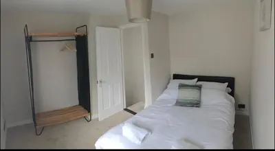 a bedroom with a white bed and a mirror at A quaint Wymondham cottage in Norwich