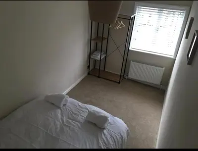 a bedroom with a white bed and a window at A quaint Wymondham cottage in Norwich