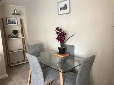 a glass table with chairs and a vase with flowers on it at A quaint Wymondham cottage in Norwich