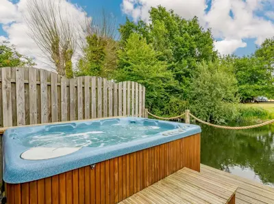 a hot tub on a wooden deck next to a fence at 16th Century Cartlodge with private hot tub in Diss