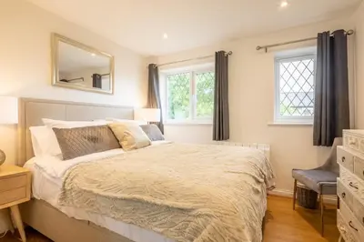 a bedroom with a bed and a mirror and windows at Delightful CENTRAL Duplex - 2 Mins To Station in Cambridge