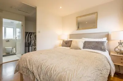 a bedroom with a large bed and a mirror at Delightful CENTRAL Duplex - 2 Mins To Station in Cambridge