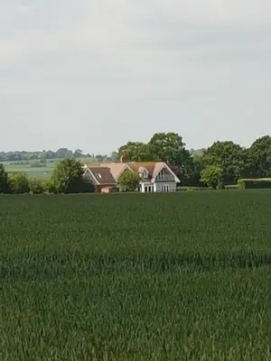 a house in the middle of a green field at Spring Paddocks B&B in Furneux Pelham