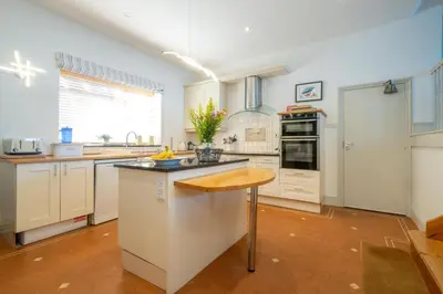 a kitchen with white cabinets and a wooden counter top at Stoney Beach - Aldeburgh Coastal Cottages in Aldeburgh