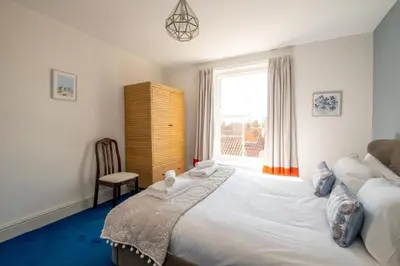 a bedroom with a bed and a chair and a window at Stoney Beach - Aldeburgh Coastal Cottages in Aldeburgh