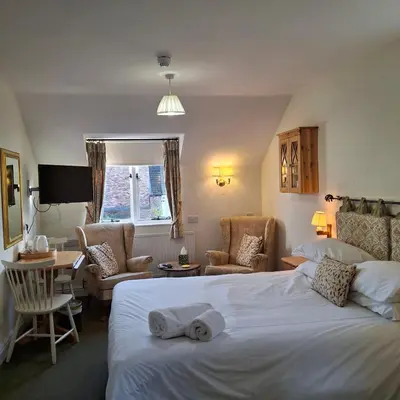 a hotel room with a bed and chairs and a table at The Abbey Hotel & Apartments in Bury Saint Edmunds