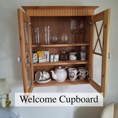 a wooden cupboard with glasses and dishes on it at The Abbey Hotel & Apartments in Bury Saint Edmunds