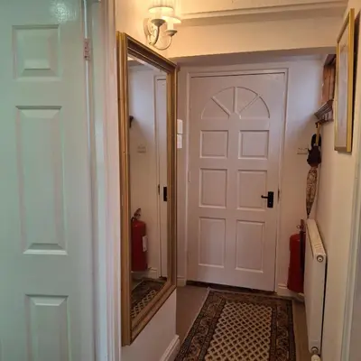 a hallway with a white door and a mirror at The Abbey Hotel & Apartments in Bury Saint Edmunds