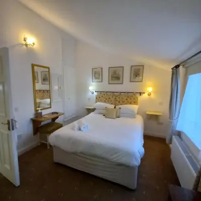 a hotel room with a large white bed and a window at The Abbey Hotel & Apartments in Bury Saint Edmunds