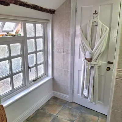 a bathroom with a robe hanging on the door at The Abbey Hotel & Apartments in Bury Saint Edmunds