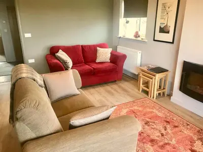 a living room with a red couch and a tv at Waterside Lodges Cambridge in Cambridge