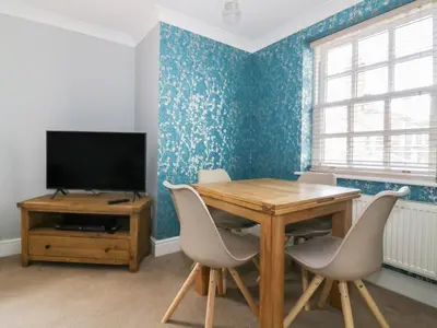 a dining room with a table and a television at The Hoist in Ely
