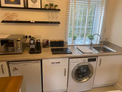 a kitchen with a washing machine and a sink at Stansted Coach House - Apartment Hotel in Elsenham