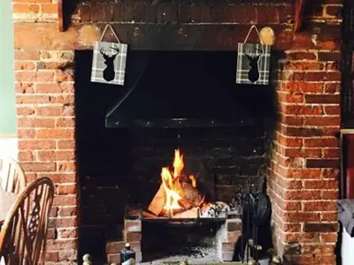 a brick fireplace with a fire in it at The Bell Inn, Rickinghall in Rickinghall