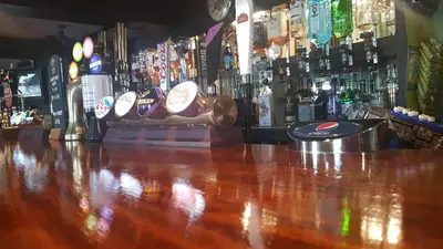 a bar with a wooden counter top and bottles of alcohol at Red Lion in Swaffham