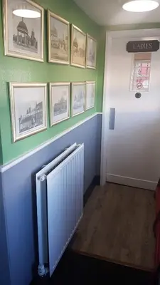 a hallway with a white radiator and pictures on the wall at Red Lion in Swaffham