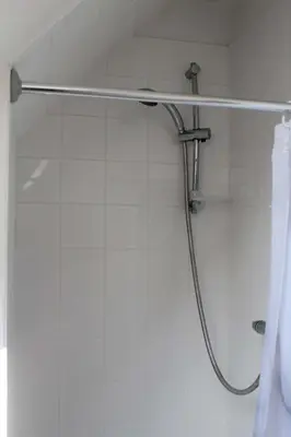 a shower with a hose in a white bathroom at The Cart Lodge in Newmarket