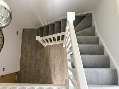 a staircase in a home with white walls and wooden floors at Rainbows End in Saint Lawrence