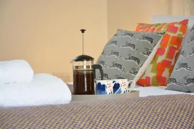 a bedroom with a bed with a lamp and a cup at Yew Tree Farm Stable, Worlingworth in Worlingworth