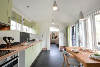 a kitchen with white cabinets and a wooden table at Yew Tree Farm Stable, Worlingworth in Worlingworth