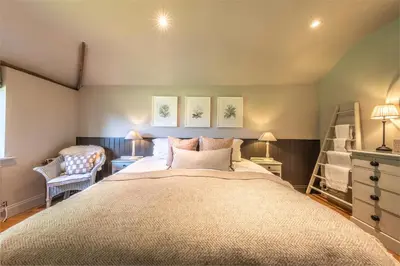 a bedroom with a large bed and a chair at Church Farm B&B Suffolk in Great Welnetham
