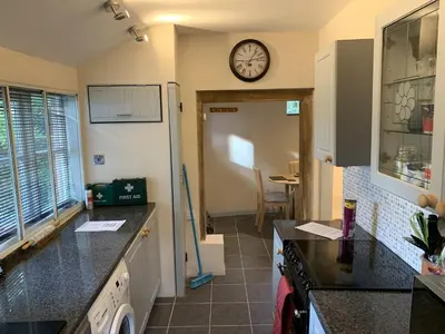 a kitchen with a clock on the wall and a counter at Myrtle cottage in Dickleburgh