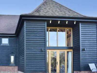a house with black siding and glass doors at Ivy Todd Barn in Ashdon