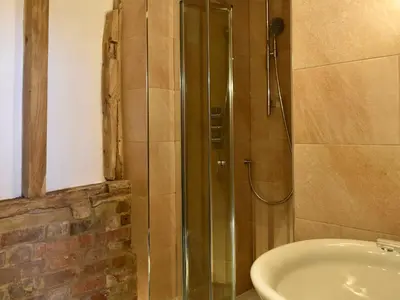 a shower with a glass door next to a sink at Ivy Todd Barn in Ashdon