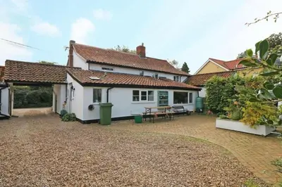 a white house with a picnic table in a yard at Cobweb Cottage Studios in Spooner Row