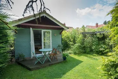 a small house with a deck with a table and chairs at Cobweb Cottage Studios in Spooner Row