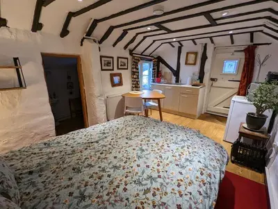 a bedroom with a large bed and a kitchen at Cobweb Cottage Studios in Spooner Row