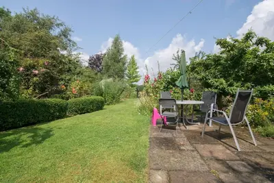 a garden with a table and chairs in the grass at Cobweb Cottage Studios in Spooner Row