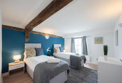 two beds in a room with blue walls at Colchester Town Duplex Apartment in Colchester